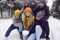Funny and playful friends have fun playing with snow while walking in winter forest.