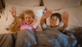 Funny playful laughing Caucasian children kids boy girl brother sister siblings happy family lying in bedroom on bed Royalty Free Stock Photo