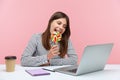 Funny playful woman licking and biting round colored lollipop on stick talking on video call at laptop sitting at workplace,