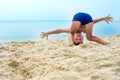 Funny playing boy standing on his head near sea