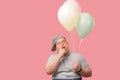 Funny plump guy standing with air balloons having doubts isoated on pink