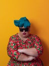 Funny plus size sexy model woman with trendy sunglasses, fashionable overweight blonde in colorful dress posing at the