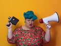 Funny plus size woman posing isolated on yellow background studio portrait. Overweight lady screaming in a megaphone