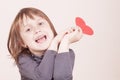 Funny portrait of cute little child girl holding red heart as symbol of love and amorousness