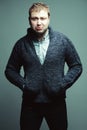 Funny portrait of handsome unhappy young man in casual trendy clothing posing over gray background. Kidult hipster. Studio shot Royalty Free Stock Photo