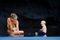 Happymother, dirty child having fun on black sand beach Royalty Free Stock Photo