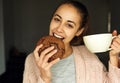 Funny portrait of happy young woman with large cup tea, biting huge piece of chocolate cookie.