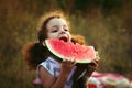 Funny portrait of an incredibly beautiful curly-haired little girl eating watermelon, healthy fruit snack, adorable toddler child Royalty Free Stock Photo