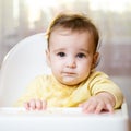 Funny portrait of a kid on a high chair indoors. The toddler looks at the camera. The child ate and smeared his face. Handsome Royalty Free Stock Photo