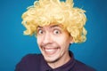 Funny portrait of a man with happy emotion on his face in the studio on blue background. Man wearing wig. Yellow hair Royalty Free Stock Photo