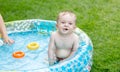 Funny portrait of smiling baby boy swimming in inflatable swimming pool at backyard Royalty Free Stock Photo