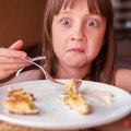 Funny portrait of young beautiful girl eating cheesecakes for breakfast
