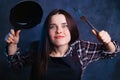 Funny portrait of young enthusiastic housewife with frying pan a