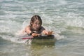 Cute portrait of a girl bodyboarding in the waves in summer