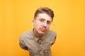 Funny portrait of a young man in a shirt on a yellow background, looking into the camera with a surprised face on a yellow Royalty Free Stock Photo