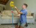 Funny portrait of young weird crazy and happy man holding mop with sunglasses as if it was his fiance kneeling and proposing marri