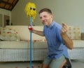 Funny portrait of young weird crazy and happy man holding mop with sunglasses as if it was his fiance kneeling and proposing marri