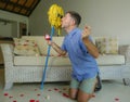 Funny portrait of young weird crazy and happy man holding mop with sunglasses as if it was his fiance kneeling and proposing marri Royalty Free Stock Photo