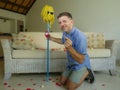 Funny portrait of young weird crazy and happy man holding mop with sunglasses as if it was his fiance kneeling and proposing marri Royalty Free Stock Photo