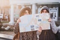 Funny positive image of fashionable girls on sunny street having fun in city, hiding behind the citymap. Travelling