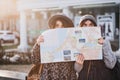 Funny positive image of fashionable girls on sunny street having fun in city, hiding behind the citymap. Travelling