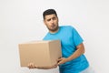 Funny positive optimistic man holding very heavy cardboard parcel, making effort to carry box.