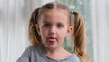 Funny preschooler girl shows tongue and looks straight