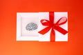 Funny present in form of a small steel copy of a human brain inside a white gift box with a red ribbon and bow on the cover