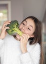 Funny preteen girl biting and eating raw broccoli. Diet and healthy food, vegetarian or vegan concept. Teenager weight control. Royalty Free Stock Photo