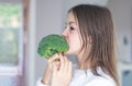 Funny preteen girl biting and eating raw broccoli. Diet and healthy food, vegetarian or vegan concept