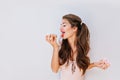 Funny pretty girl with long hair holding colorful donuts. Attractive young woman in pink body suit licking delicious Royalty Free Stock Photo