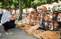 Funny priest with other clay characters at an outdoor stall of a ceramic fair in the city of Zamora admired by a tourist.