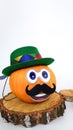 a funny pumpkin with a hat on its head and a mustache stands on a round wooden podium on a light background. concepts Royalty Free Stock Photo