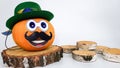 a funny pumpkin with a hat on its head and a mustache stands on a round wooden podium on a light background. concepts Royalty Free Stock Photo