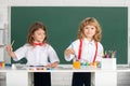 Funny pupils draws in classroom on school blackboard background. School friends kids boy and girl painting together in Royalty Free Stock Photo