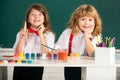 Funny pupils draws in classroom on school blackboard background. School friends kids boy and girl painting together in