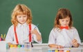 Funny pupils draws in classroom. School friends kids boy and girl painting together in class on school blackboard