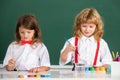 Funny pupils draws in classroom. School friends kids boy and girl painting together in class on school blackboard