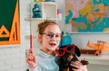 Funny puppi and pupil. Puppy in glasses. Funny pupil looking for a drawing concept. Friendly child in classroom near