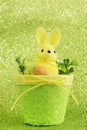 Funny rabbit with a carrot in a basket with flowers. Lovely easter toy. Greeting card for Easter. Vertical orientation