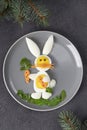 Funny rabbit made from boiled eggs, peeled carrots and arugula on gray plate. Creative food idea for kids, Top view