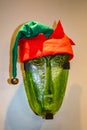 Funny red and green Christmas elf hat on elf like face wall decoration in office during the holidays