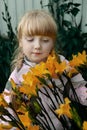 Funny red-haired girl with a bouquet of yellow lilies laughs. Portrait of a cheerful child Royalty Free Stock Photo