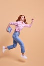 Funny redhead female student rushing forwards with book in hands, hurry to university Royalty Free Stock Photo