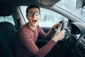 Ridiculous idiotic nerd driver in big eyeglasses holding the steering wheel and smiling to the camera. Concept of a Royalty Free Stock Photo