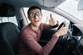 Ridiculous idiotic nerd driver in big eyeglasses holding the steering wheel and smiling to the camera. Concept of a Royalty Free Stock Photo