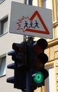 funny road sign with children coming out of the triangle and the traffic light by the school