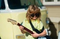 Funny rock child with guitar. Little boy in sunglasses. Kids music concept. Child musician playing the guitar like a Royalty Free Stock Photo