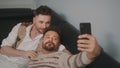 Funny romantic male gay couple using smartphone for video call.