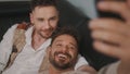 Funny romantic male gay couple using smartphone for video call.